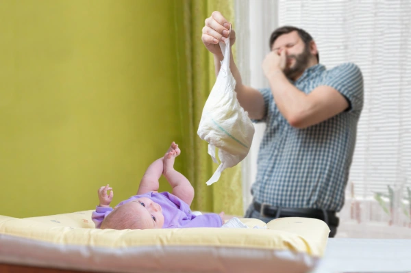Far og baby med ildelugtende ble ved puslebord